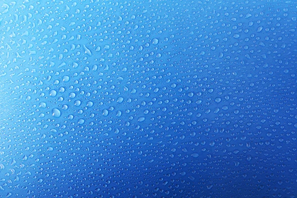 Gouttes d'eau sur verre sur fond bleu — Photo