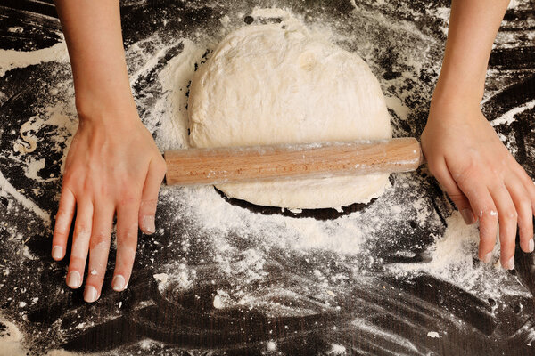 Making dough by female hands on wooden table background