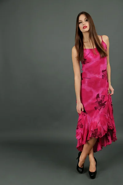 Beautiful young woman in long pink dress on dark gray background — Stock Photo, Image