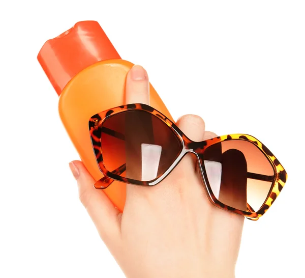 Bottle of suntan cream and sunglasses in female hands isolated on white — Stock Photo, Image