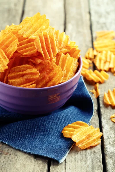 Delicious potato chips in bowl on wooden table close-up — Stock Photo, Image