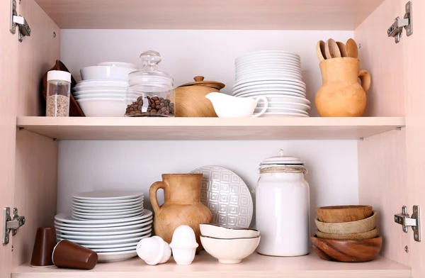 Ustensiles de cuisine et vaisselle sur étagères en bois — Photo