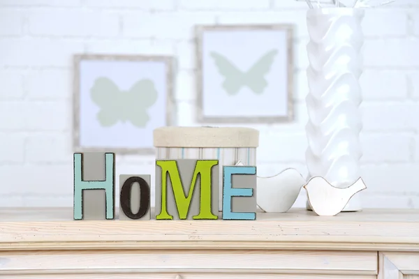 Casa em letras coloridas, em interior branco claro, na prateleira de madeira — Fotografia de Stock