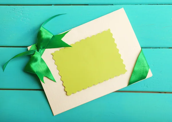 Card decorated with green bow on wooden background — Stock Photo, Image