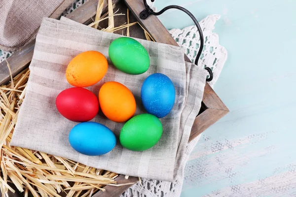 Pasen eieren op houten lade, op kleurrijke achtergrond — Stockfoto
