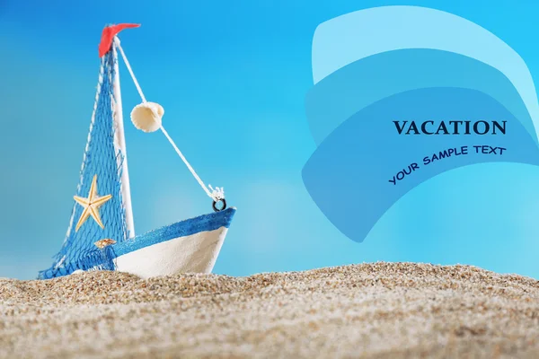 青色の背景色の砂の上の船の玩具モデル — ストック写真