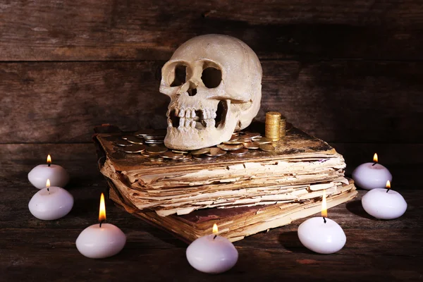 Naturaleza muerta con cráneo humano, libro retro y luz de las velas en la mesa de madera, primer plano —  Fotos de Stock