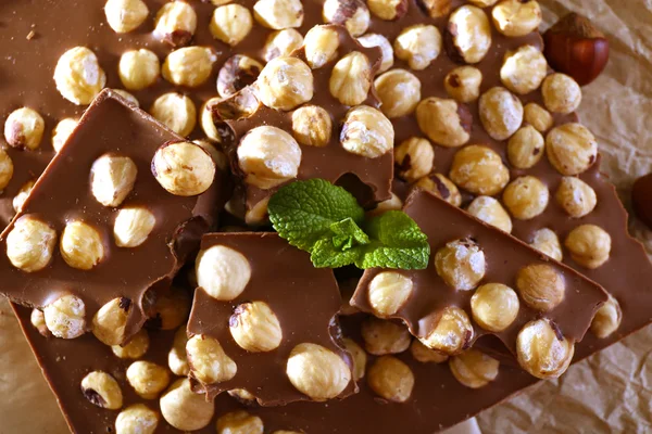 Chocolate with nuts on parchment, closeup — Stock Photo, Image