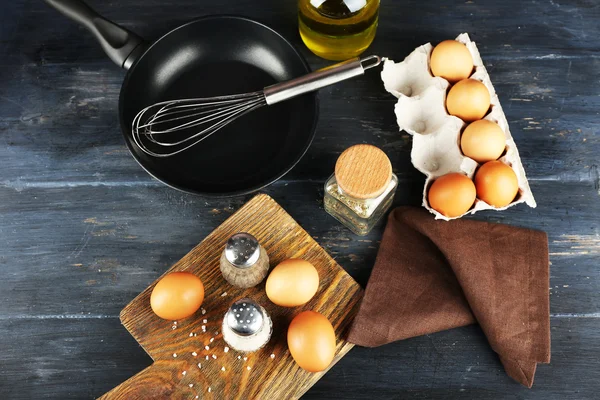 Stilleven met eieren en pan op houten tafel, bovenaanzicht — Stockfoto