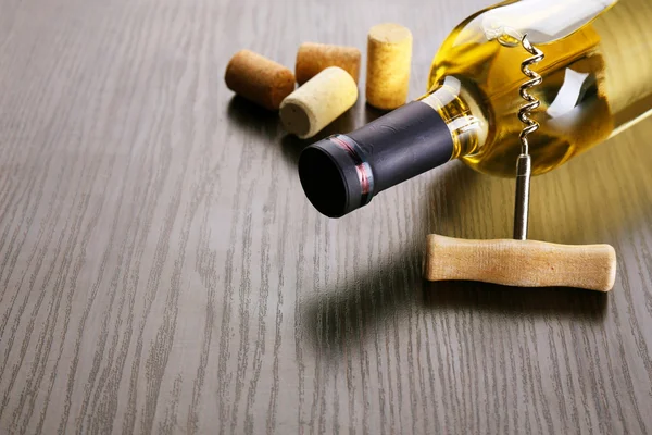 Бутылка вина с пробками и штопор на деревянном фоне — стоковое фото