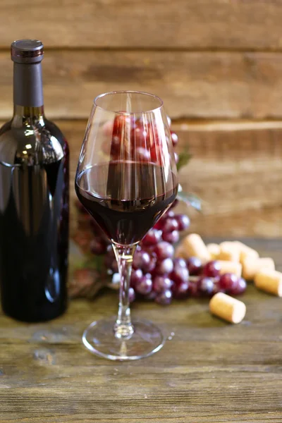 Μπουκάλι και ποτήρι κρασί με το σταφύλι σε ξύλινα φόντο — Φωτογραφία Αρχείου
