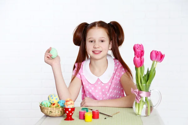 Aranyos lány díszíti a húsvéti tojás, a világos háttér — Stock Fotó