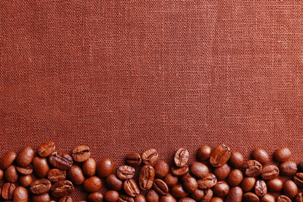 Frame of coffee beans on color sackcloth background — Stock Photo, Image