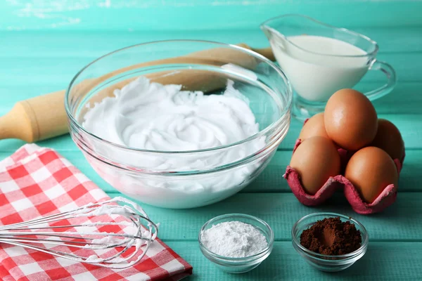 Geschlagenes Eiweiß für Sahne auf farbigem Holzhintergrund — Stockfoto