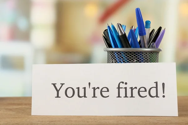 Mensagem You 're Fired on wooden table, on blurred background — Fotografia de Stock