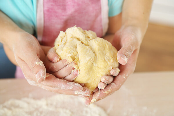 Little girl preparing cookies with mother in kitchen, close-up