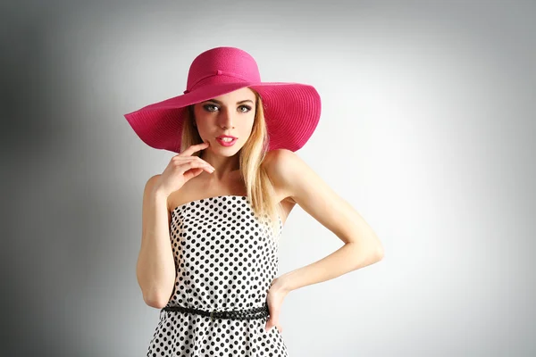 Ekspresyjny młody model w różowy kapelusz na szarym tle — Zdjęcie stockowe