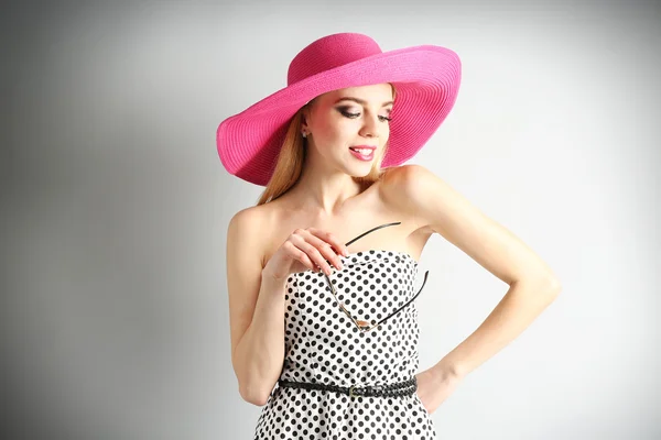 Εκφραστική νεαρό μοντέλο κατά τα ροζ καπέλο με γυαλιά ηλίου σε γκρι φόντο — Φωτογραφία Αρχείου