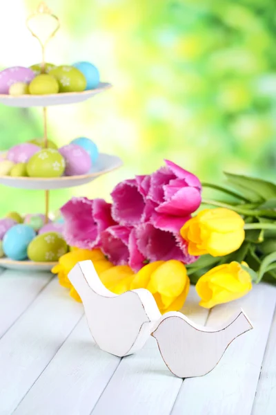 Velikonoční dekorace, vejce a tulipány na stole na přírodní pozadí — Stock fotografie