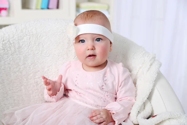 Carino neonata in abito rosa seduto in poltrona, su sfondo interno casa — Foto Stock