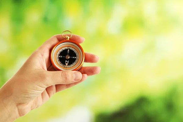 Female hand with compass on bright blurred background — Stock Photo, Image