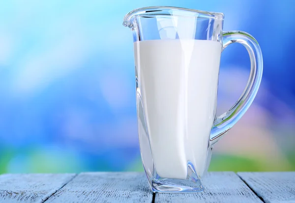 Tillbringare med mjölk på träbord på naturliga bakgrund — Stockfoto