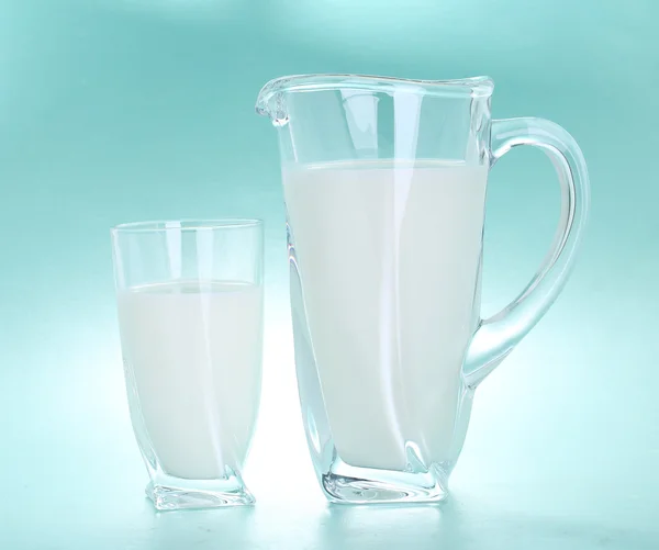 Pitcher et verre de lait sur fond bleu — Photo