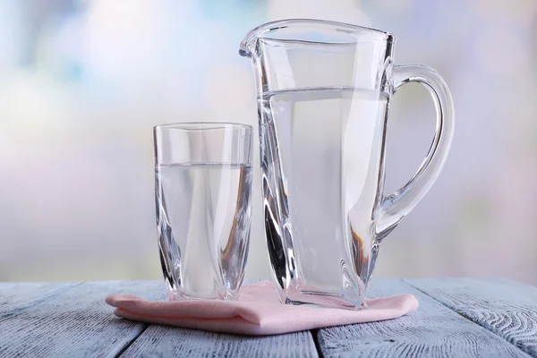 Glas werper en glas water op houten tafel op lichte achtergrond — Stockfoto