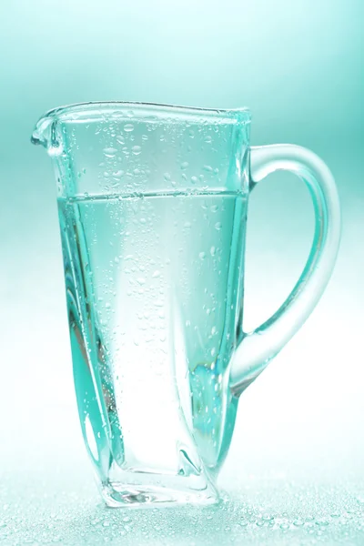 青色の背景に水のガラス ピッチャー — ストック写真