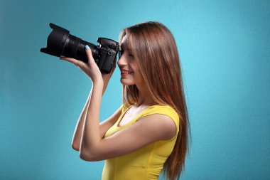 Mavi arka plan üzerinde çekim genç kadın fotoğrafçı