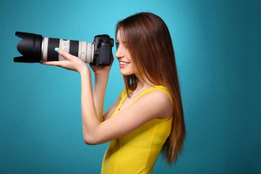 Mavi arka plan üzerinde çekim genç kadın fotoğrafçı