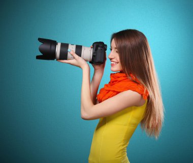 Mavi arka plan üzerinde çekim genç kadın fotoğrafçı