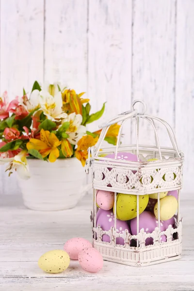 Paaseieren in decoratieve cage en bloemen — Stockfoto