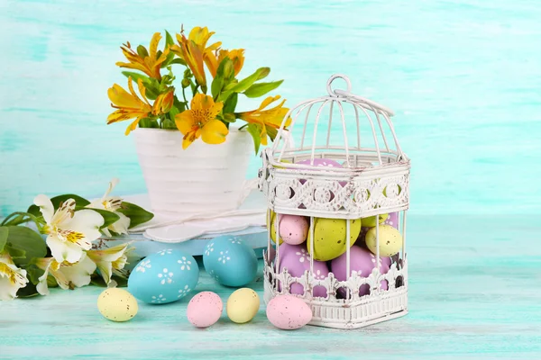 Ovos de Páscoa em gaiola decorativa e flores — Fotografia de Stock