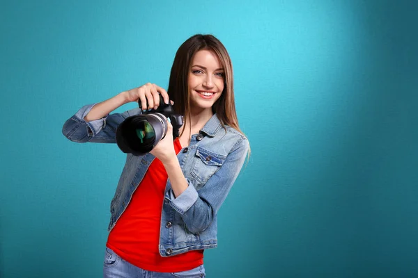 Jovem fotógrafa tirar fotos no fundo azul — Fotografia de Stock