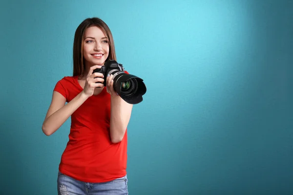 Joven fotógrafa tomando fotos sobre fondo azul — Foto de Stock