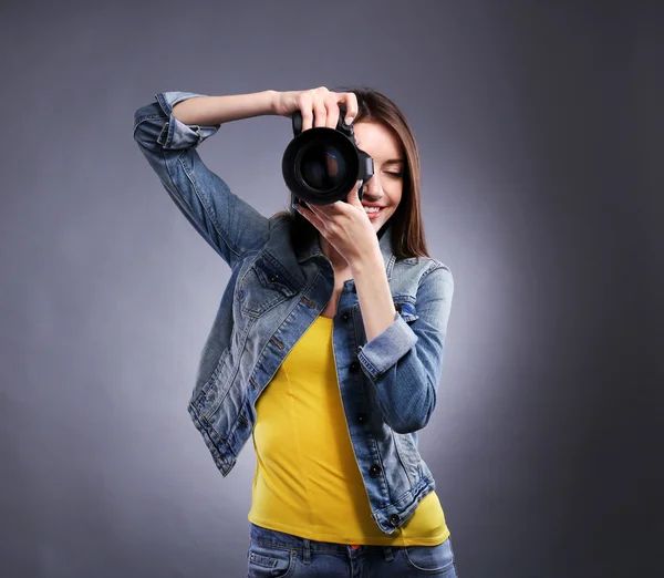 Joven fotógrafa tomando fotos sobre fondo gris —  Fotos de Stock