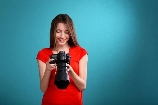 Молода жінка-фотограф фотографує на синьому фоні — стокове фото