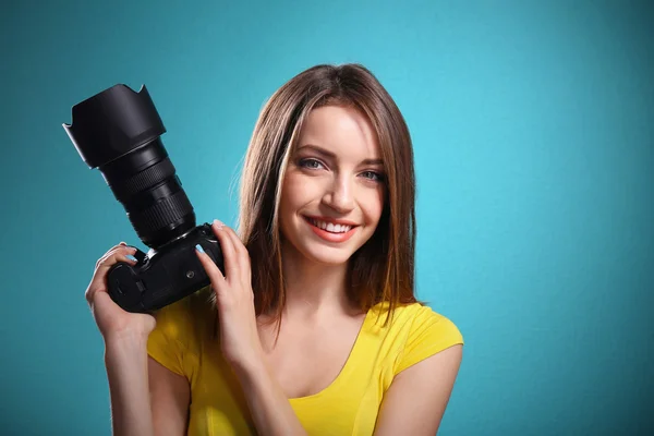 Молодая женщина фотограф делает фотографии на синем фоне — стоковое фото