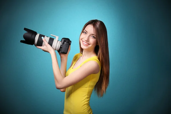 Jovem fotógrafa tirar fotos no fundo azul — Fotografia de Stock