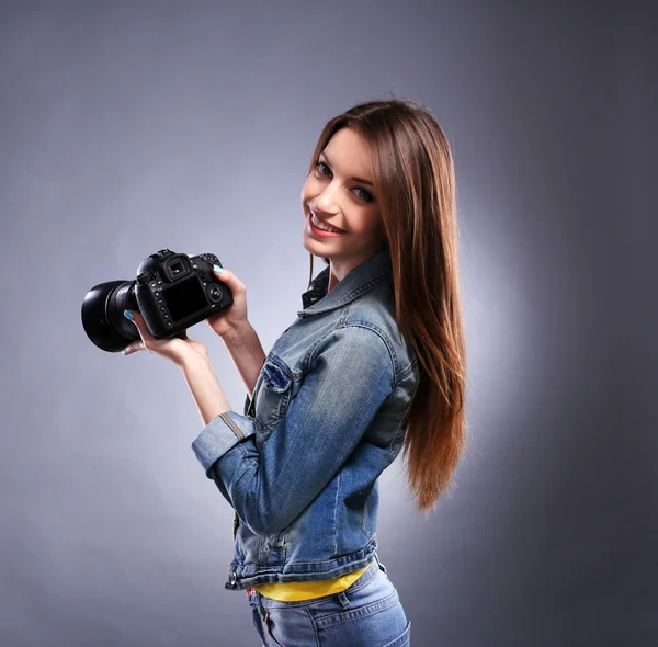 灰色の背景に写真を撮る若い女性写真家 — ストック写真