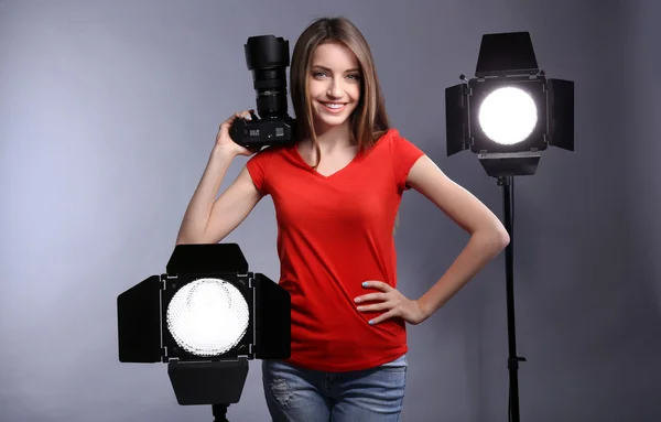 Young female photographer taking photos on grey background