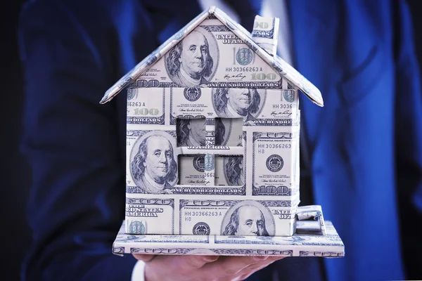 Model of house made of money in male hand, close up — Stock Photo, Image