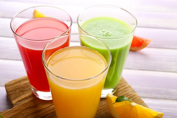 Färska juicer med frukter på träbord — Stockfoto