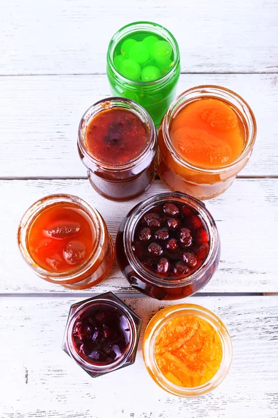 Hausgemachte Gläser mit Früchten Marmelade auf farbigen Holzplanken Hintergrund — Stockfoto