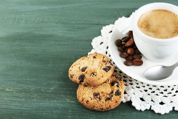 Cup of coffee and tasty cookie on color wooden background — Stock Photo, Image