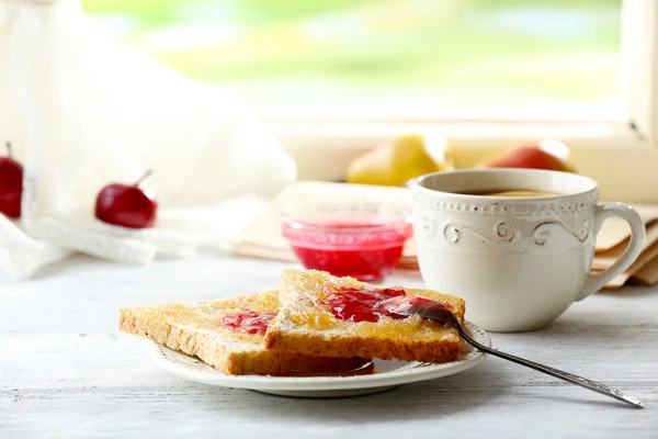 Rostat bröd med sylt på plattan och kopp te på ljus bakgrund — Stockfoto