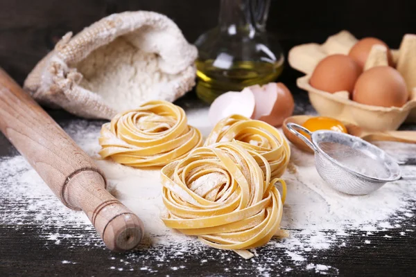 Raw homemade pasta and ingredients for pasta on wooden background — Stock Photo, Image