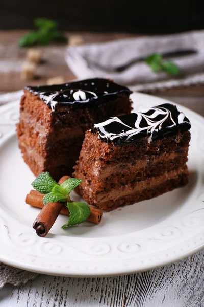 Smakelijke stukjes chocolade cake met munt en kaneel op houten tafel achtergrond — Stockfoto