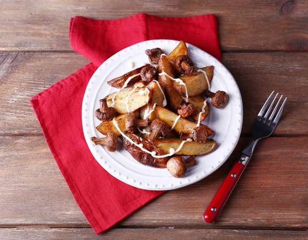 Batatas assadas com cogumelos e molho na chapa na mesa de madeira — Fotografia de Stock